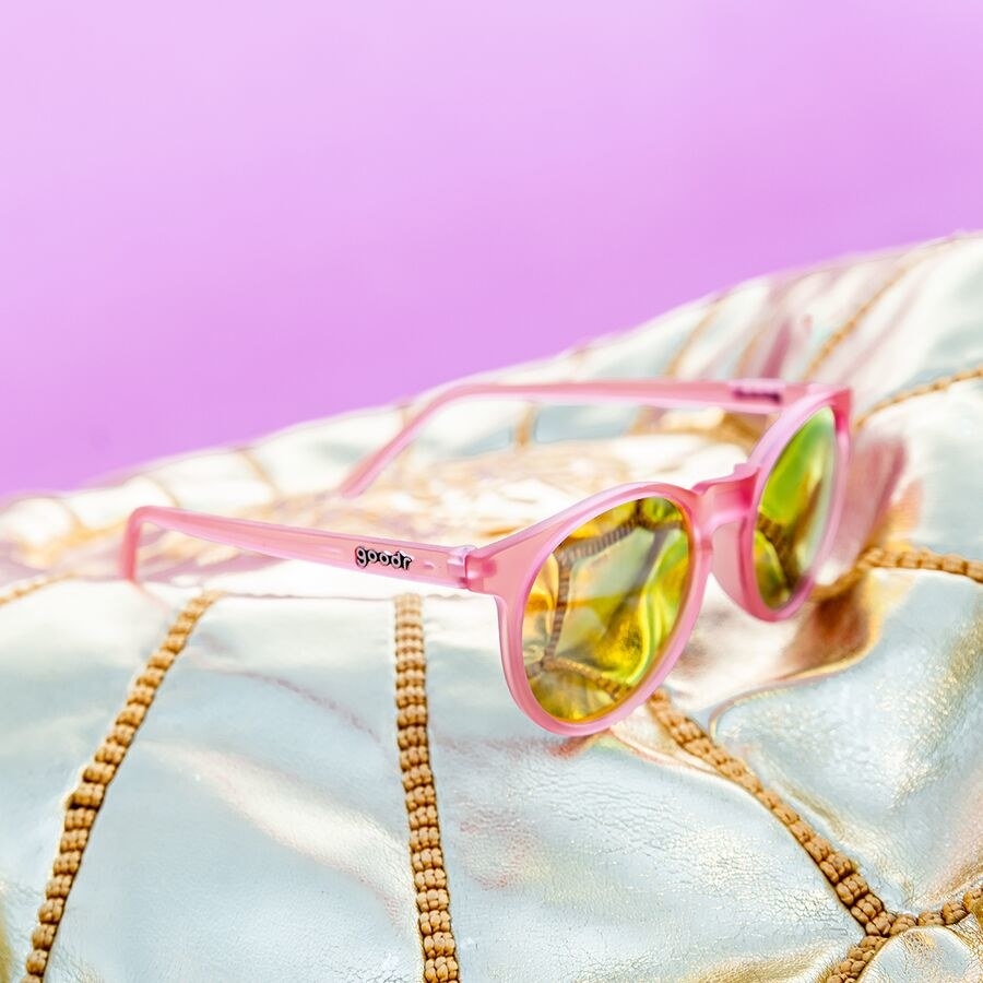 Polarized pink sunglasses with yellow lenses on white cushion