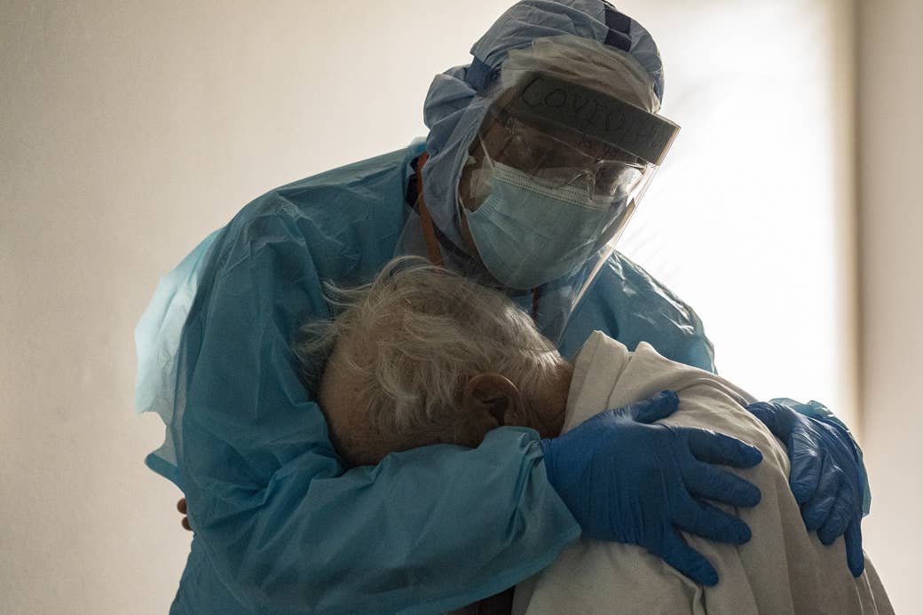 A man in protective gear hugs an elderly man