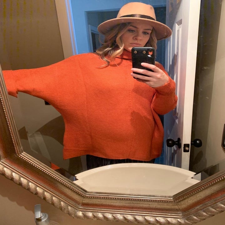 pregnant reviewer wearing the sweater in red orange