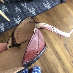 A reviewer photo of a leather shoe with an ankle strap that has begun to tear 