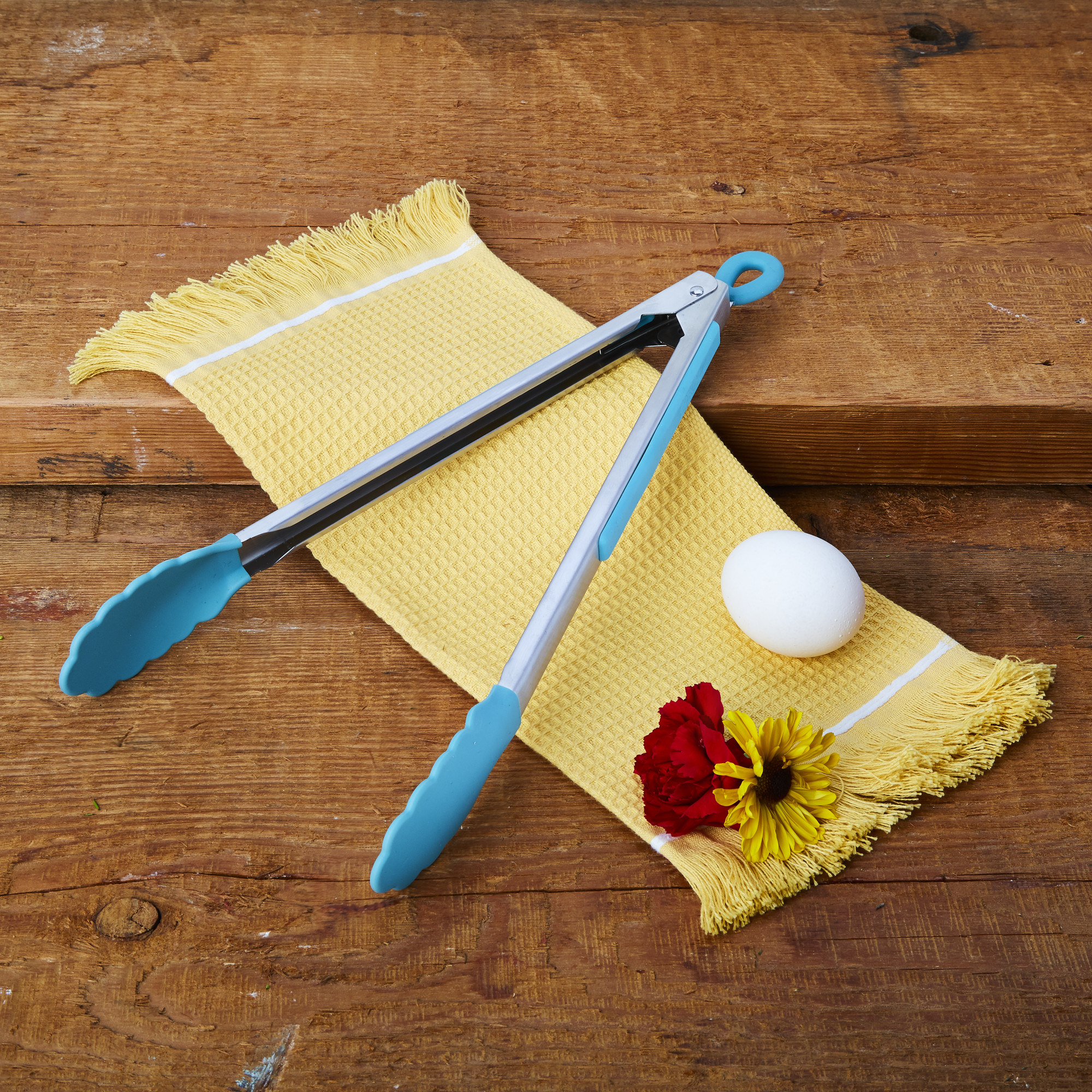 The blue tongs on a yellow kitchen towel