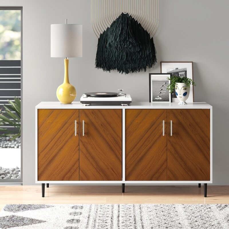 The sideboard, which has wood paneled doors, white sides and top, and slim metal handles