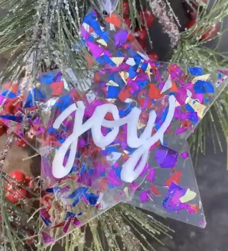 A star ornament covered in purple and blue confetti 