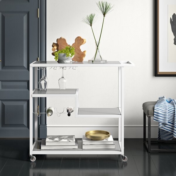 The bar cart, which has 3 levels, holds 4 wine bottles and 8 wine glasses