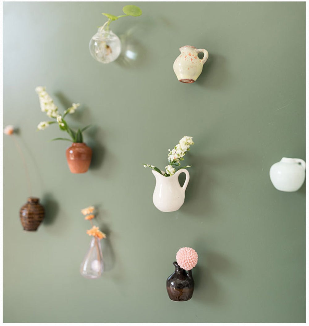 eight different tiny vases, some with plants inside of them