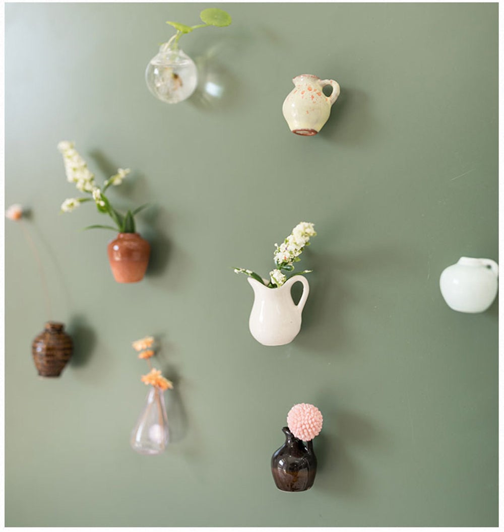 eight different tiny vases, some with plants inside of them 