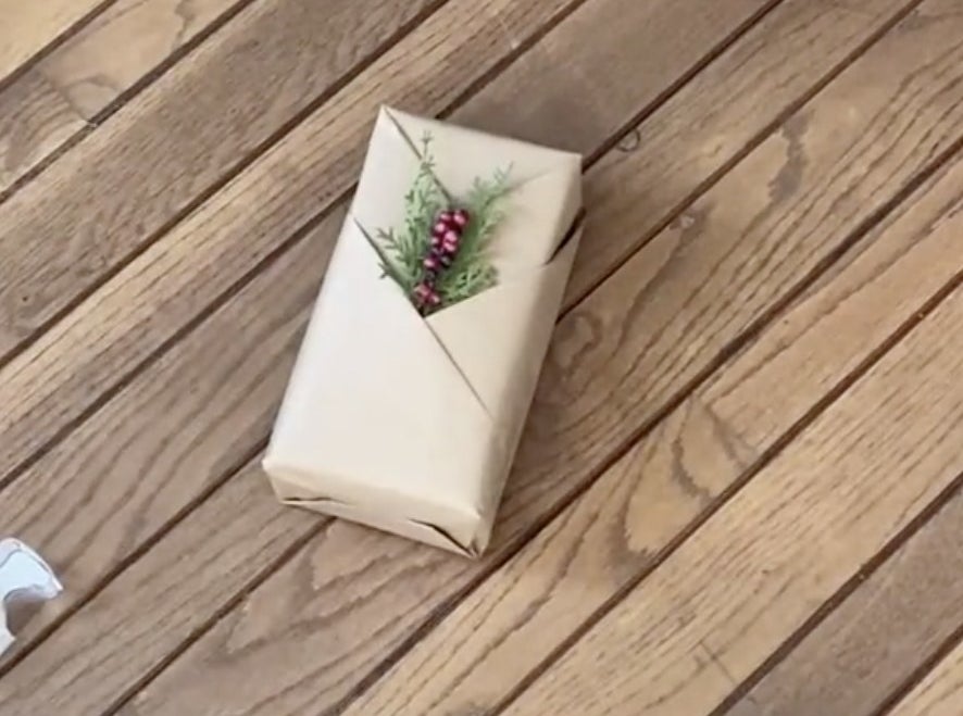 A brown paper present with diagonal folds and a Christmas tree sprig attached