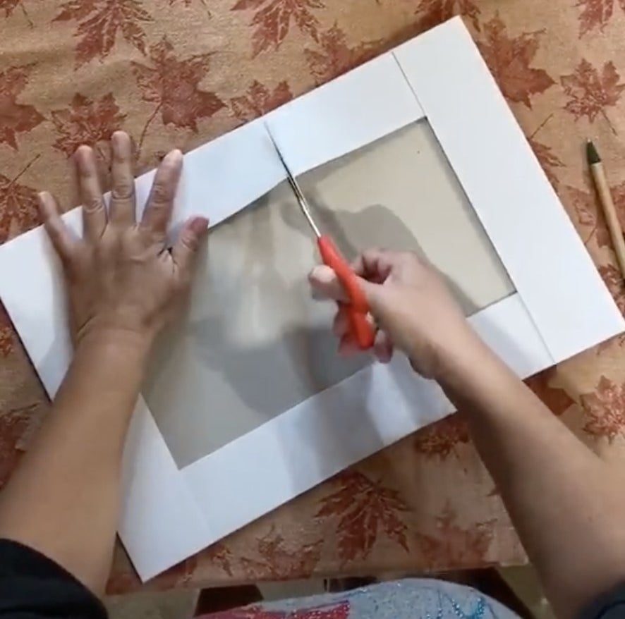 A woman cuts a cardboard box with scissors 