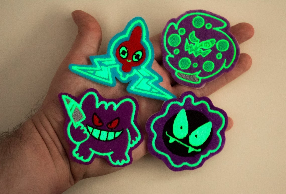 hand holds patches that look like ghastly, gengar, spiritomb, and rotom