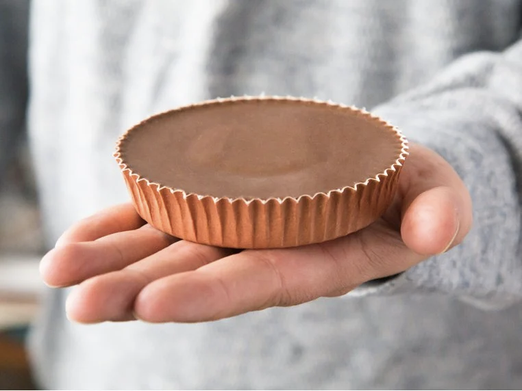 model holds jumbo peanut butter cup that's as large as their palm
