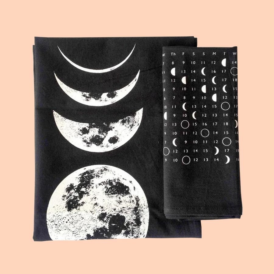 black towels, one with a moon calendar and the other with large moon phases illustration