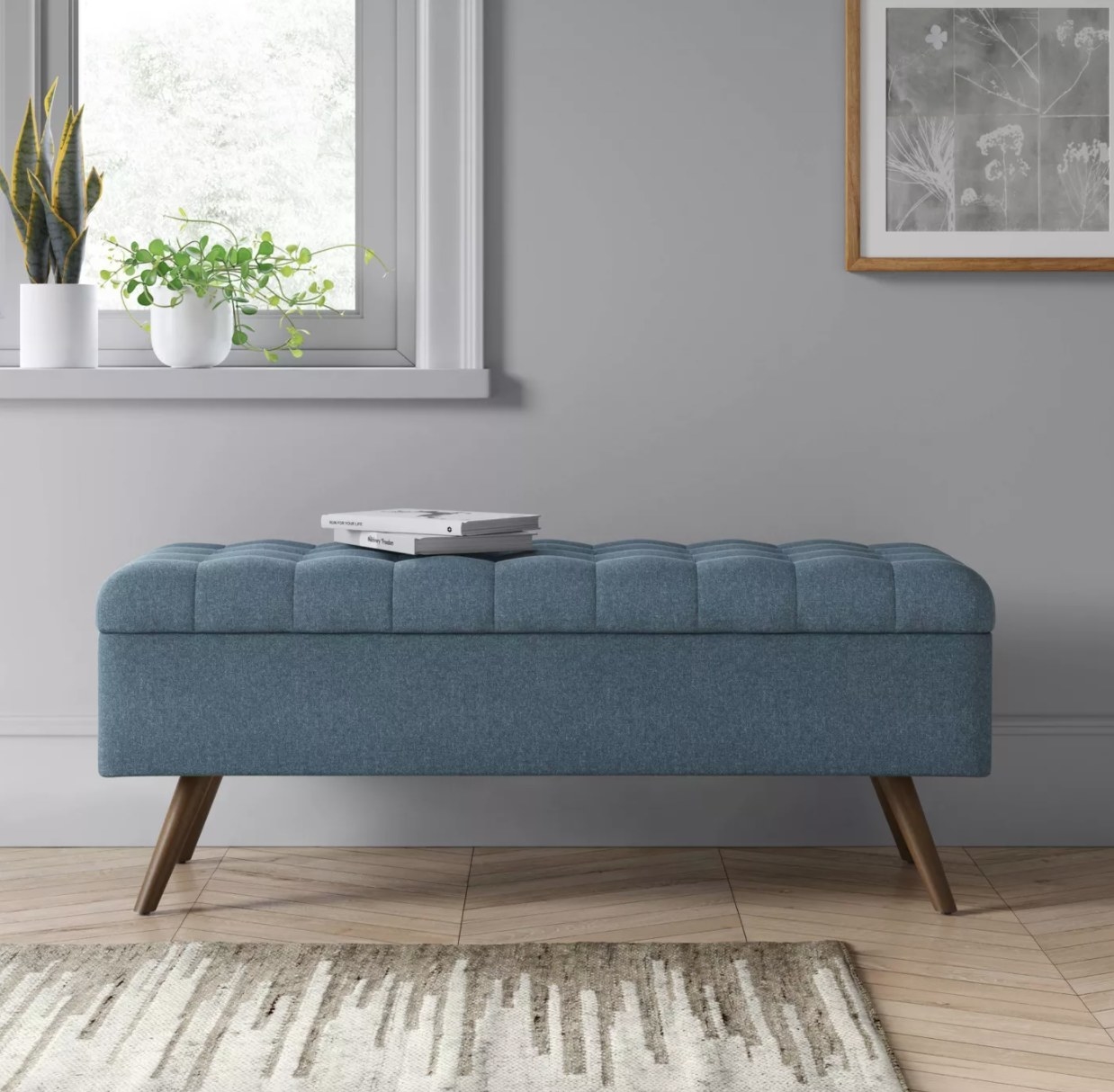 A blue tufted storage bench with wooden legs