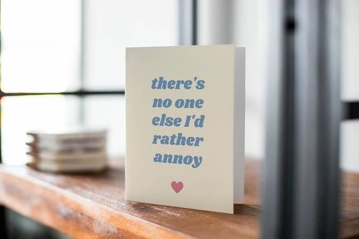 A white card that says "There's no one else I'd rather annoy" in blue type, with a red heart