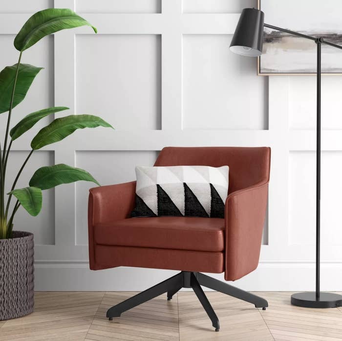 A brown faux leather accent chair with black metal swivel base