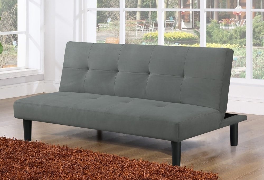 a grey upholstered futon couch in a living room