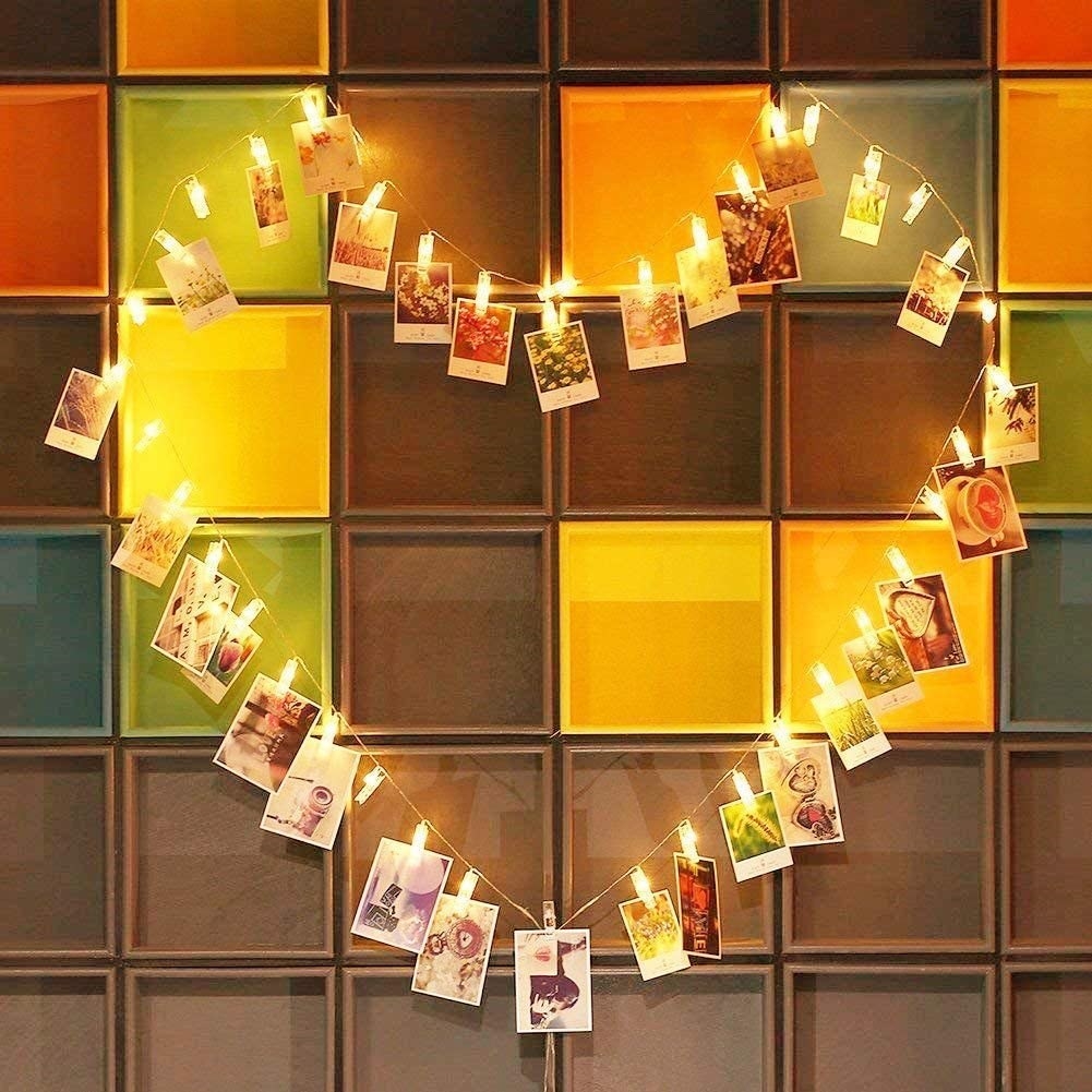 Glowing fairy lights in the shape of a heart with pictures hanging from them