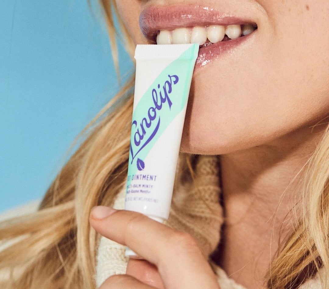 A person holding a Lanolips 101 tube to their mouth