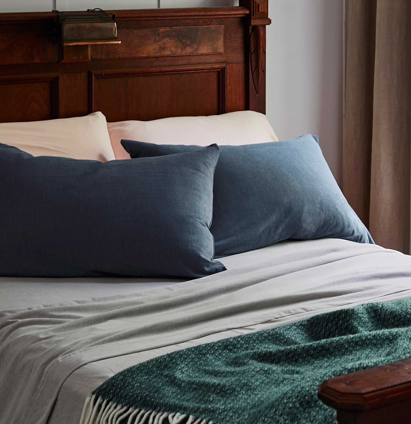 A cozy bed with pillows, pillowcases, sheets, and a throw blanket