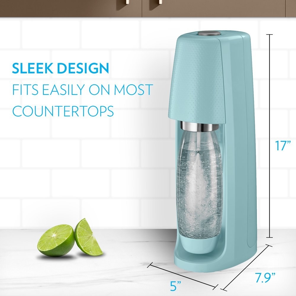 a turquoise sodastream carbonating water on a counter next to two pieces of lime