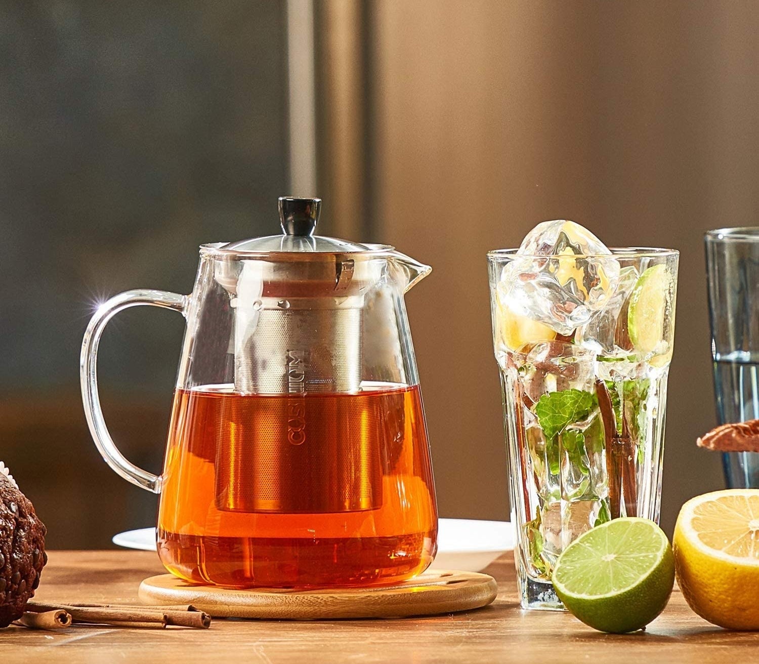 A glass teapot full of tea next to a glass of ice
