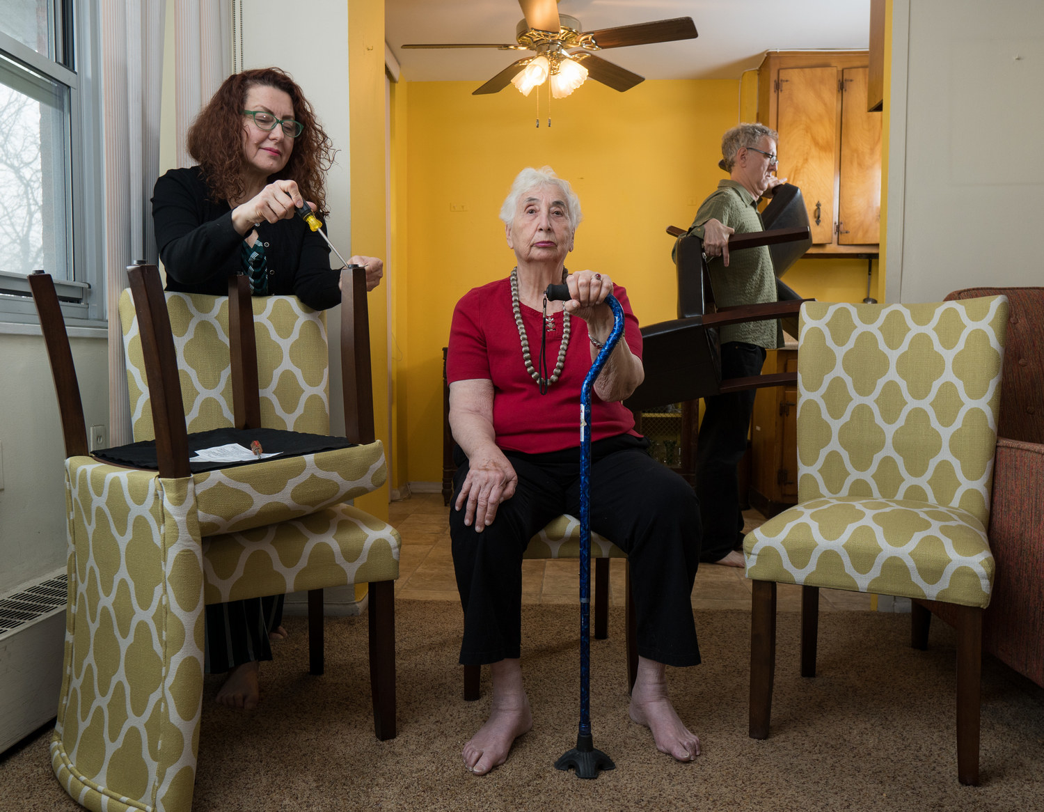 A woman with a walker and two other people fixing chairs