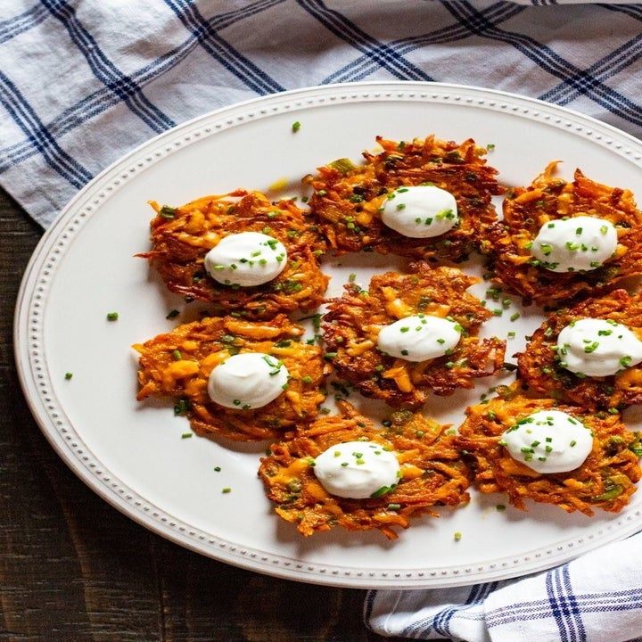 Sweet potato latkes topped with sour cream on a plate.