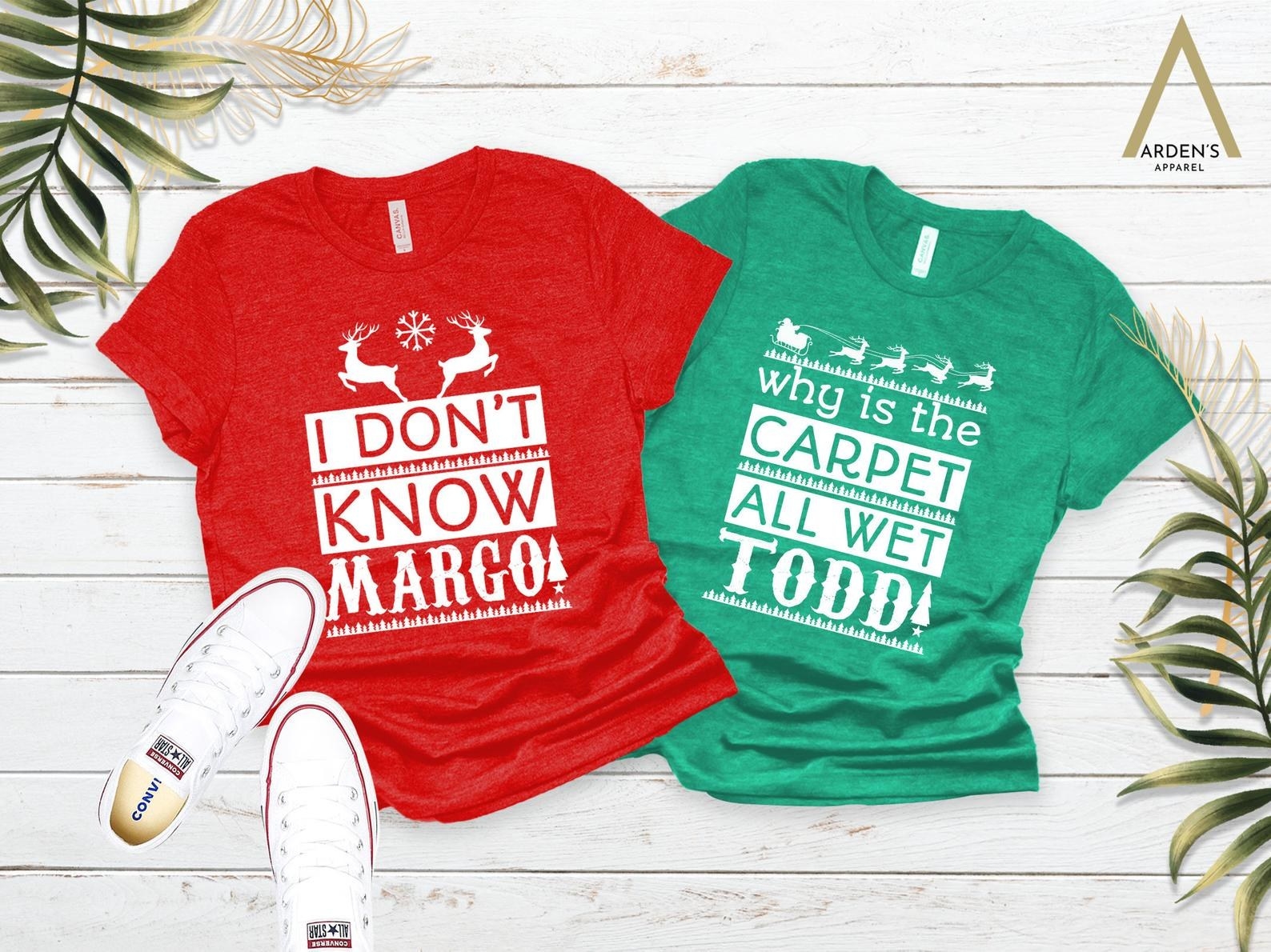 a red tee that says &quot;I don&#x27;t know margo&quot; and a green tee that says &quot;why is the carpet all wet todd&quot;