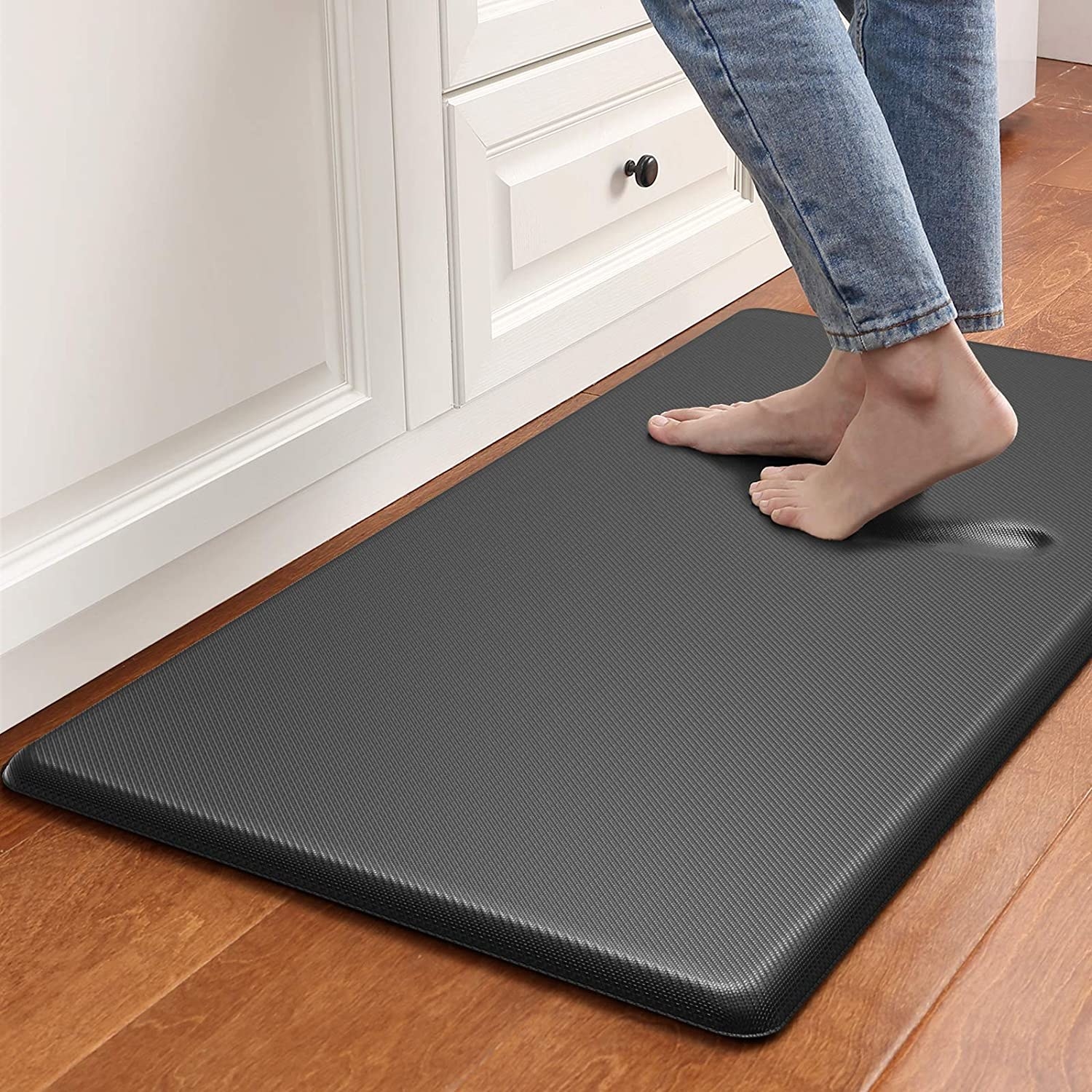 The rectangle mat in dark grey with a model standing on it, showing that it forms to the foot