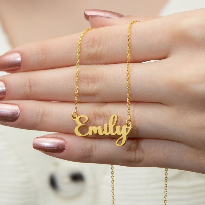 person holding gold "Emily" necklace