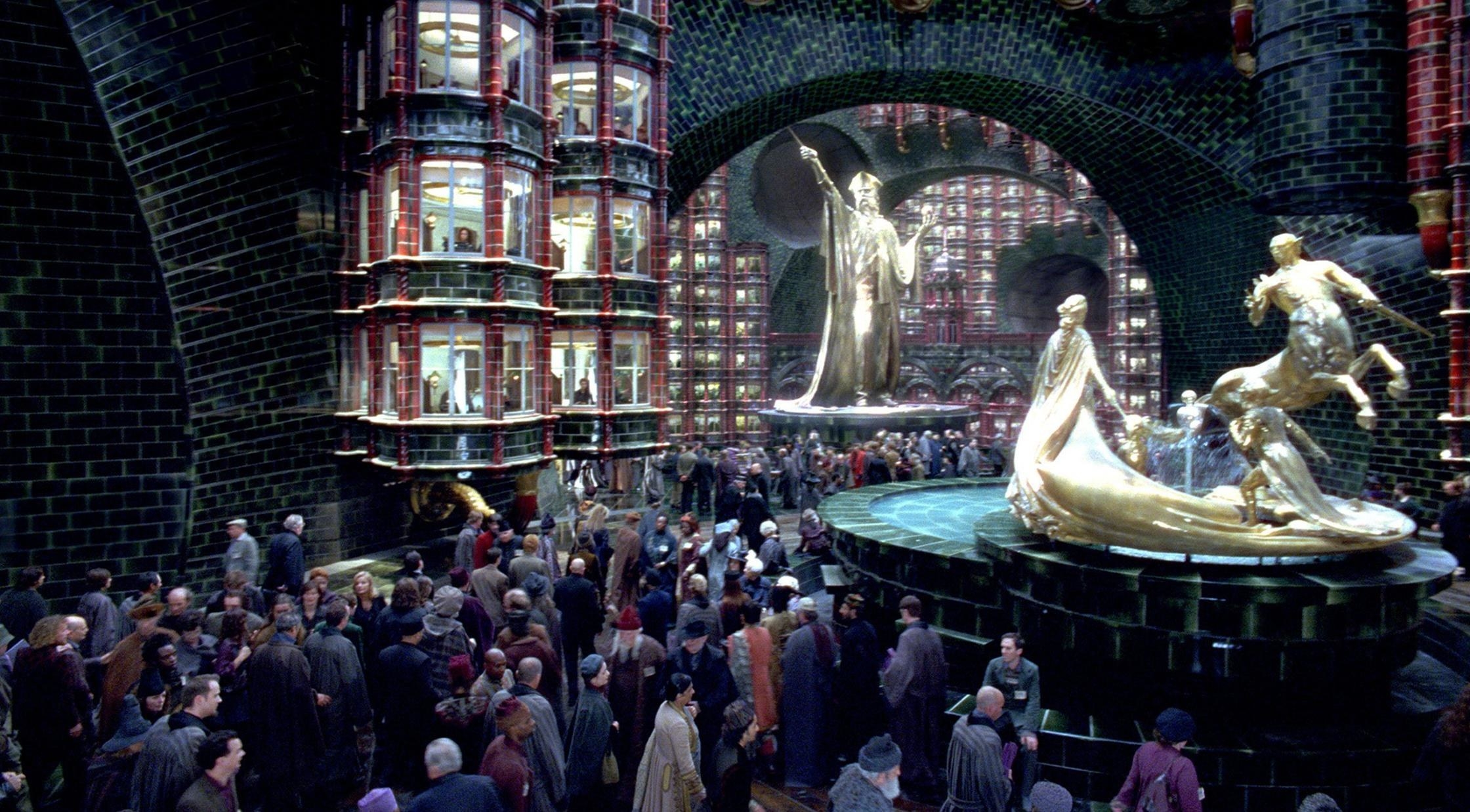 The ministry of magic main entrance with giant gold statues and bustling with workers 