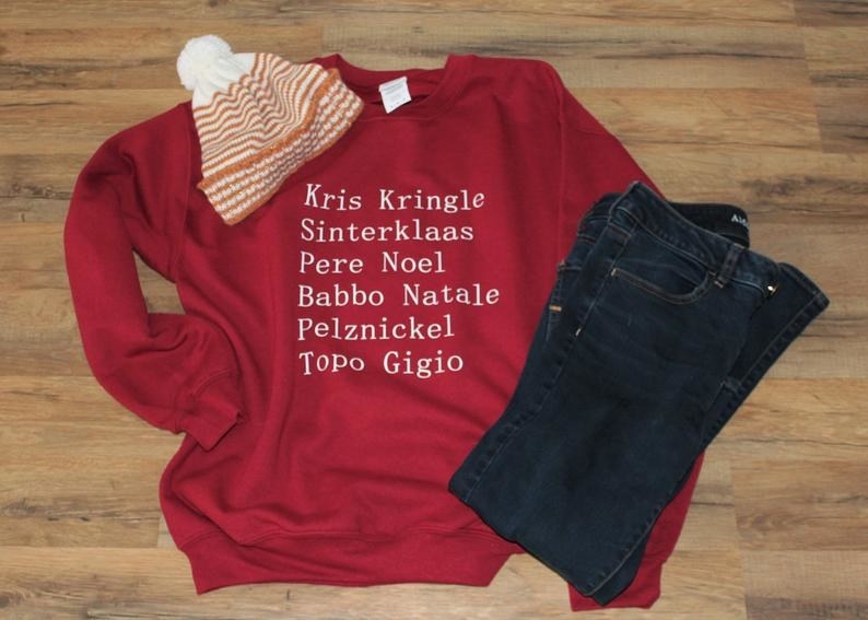 a red sweatshirt with the words &quot;kris kringle, sinterklaas, pere noel, babbo natale, pelznickel, and topo gigio&quot; on it 