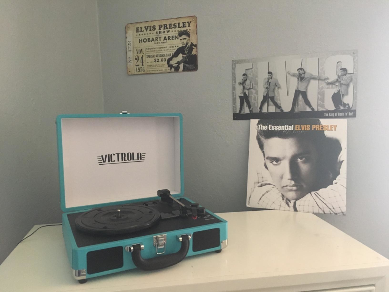 Reviewer pic of the rectangle record player that looks like a suitcase in teal, open, showing the black turn table inside
