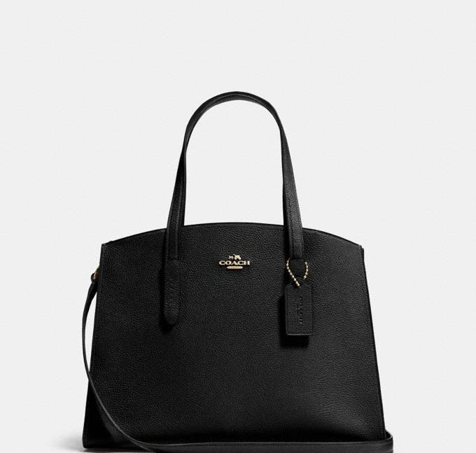 a black carryall bag with gold accents and the coach logo