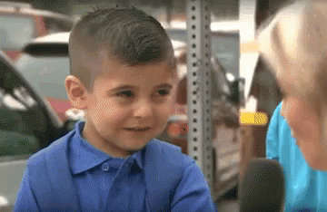 A little boy talking to a news reporters smiling and trying to keep it together before breaking down crying