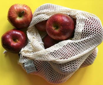 One of the mesh produce bags filled with red apples 