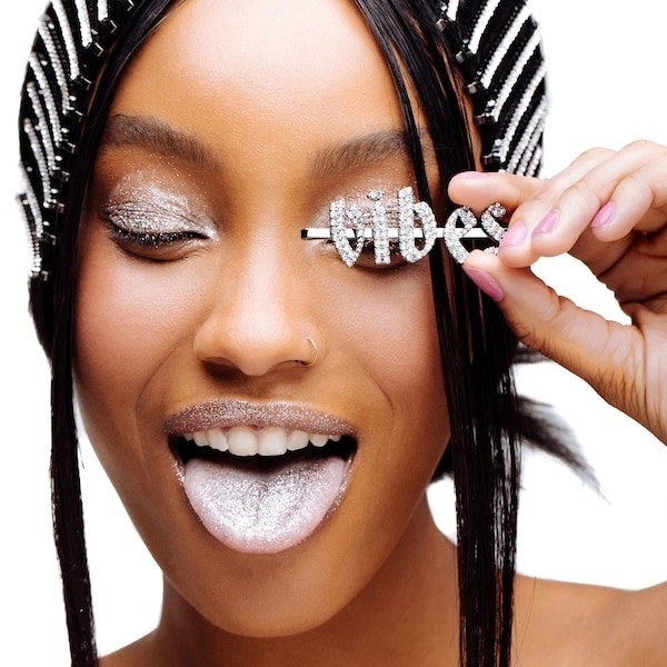 A glamorous woman holding up a bobby pin with the word "vibes" on it