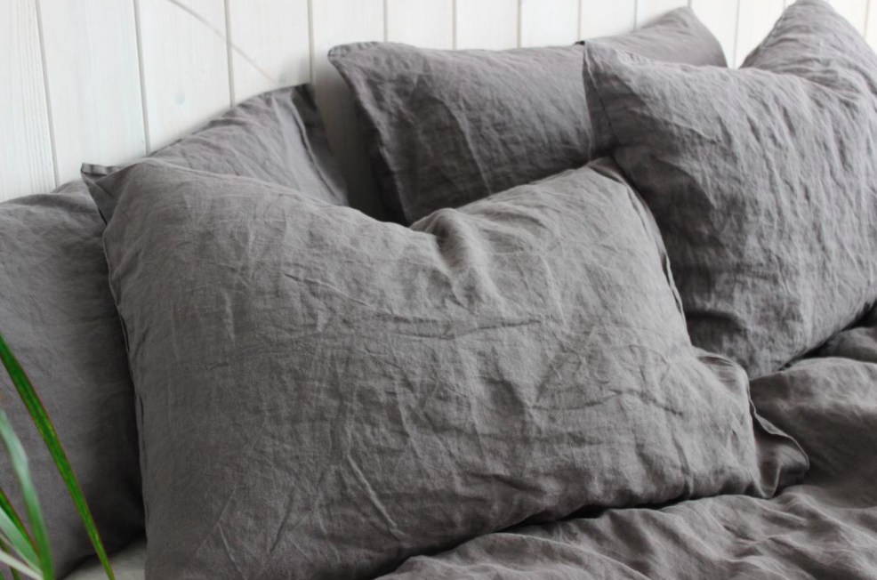 A set of four wrinkled linen pillowcases on a bed