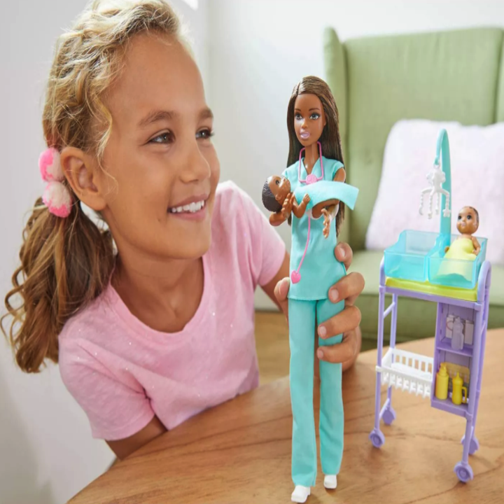kid playing with the barbie and twin baby dolls and a hospital bed 