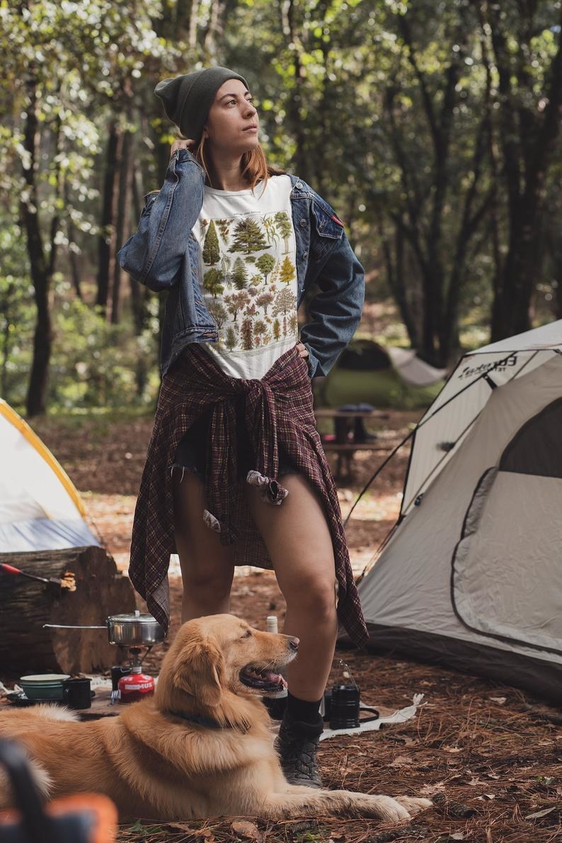 a model wearing the shirt at a campsite with a dog and a tent