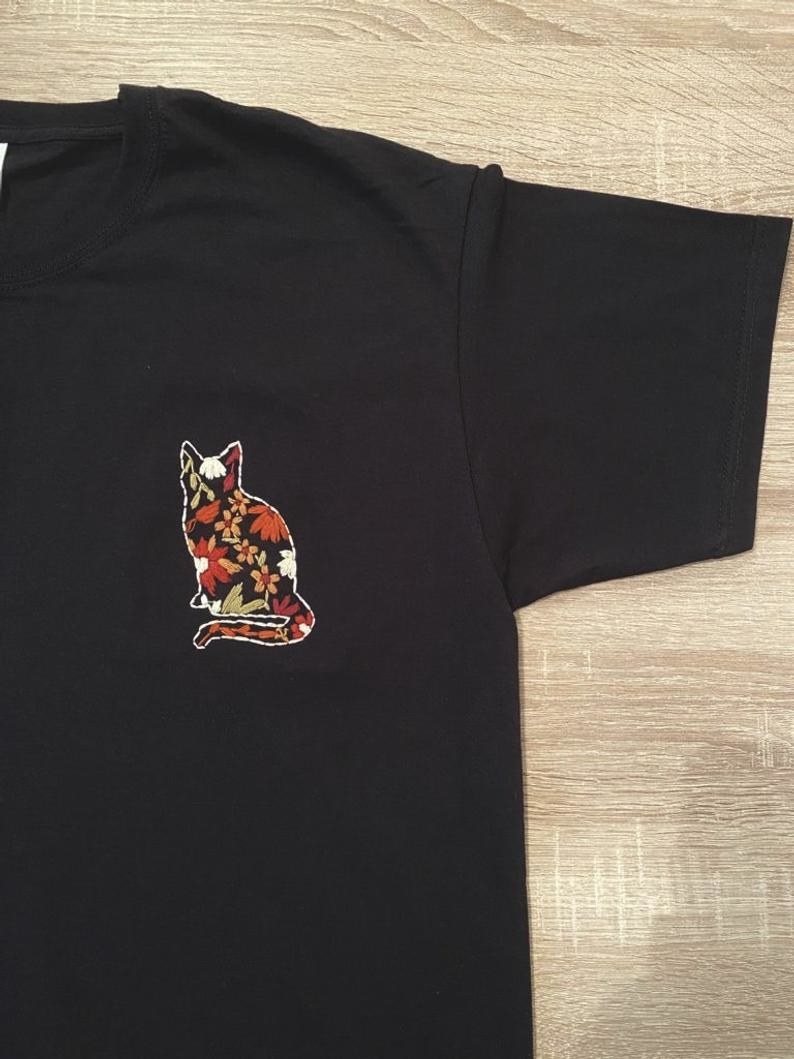 the t-shirt in black with a colorful embroidered cat in the right corner