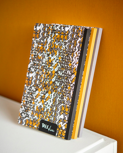A set of paper notebooks with graphic covers stacked neatly next to one another