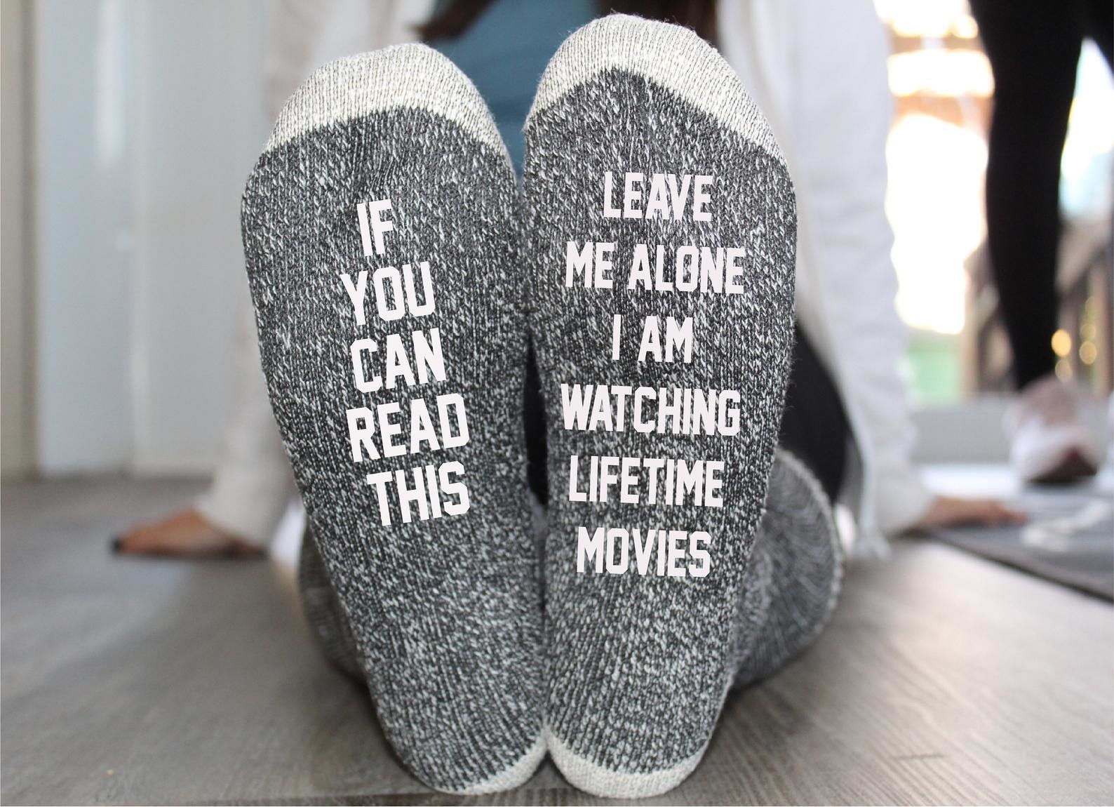 a model wearing gray socks with one sock that says &quot;if you can read this&quot; on one foot and &quot;leave me alone I am watching lifetime movies&quot; on the other