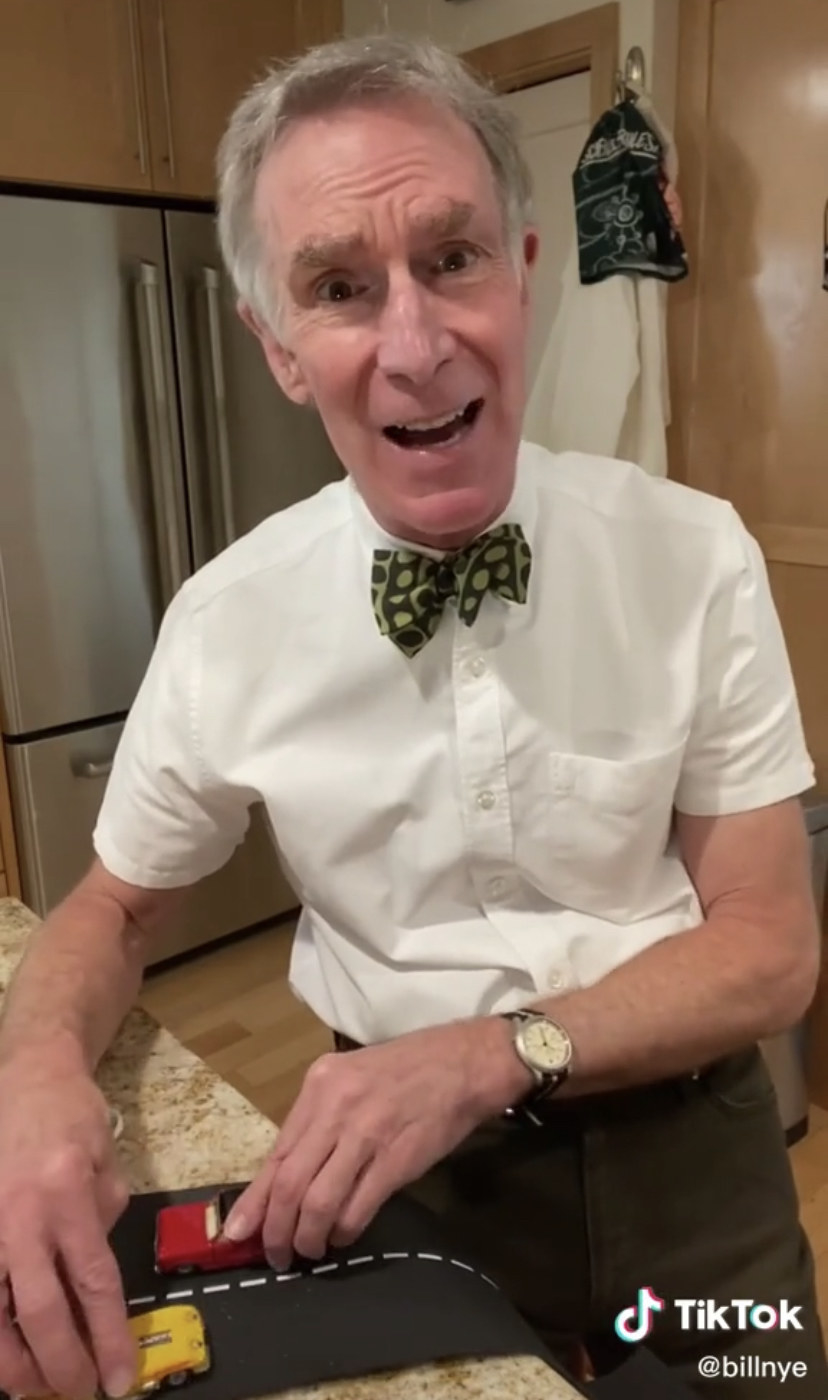 Bill Nye holding two toy cars