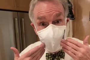 Bill Nye wearing a face mask and pointing to his face