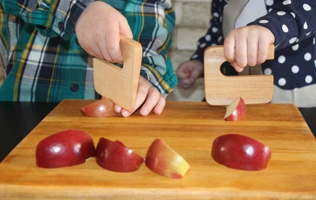 Two child models cutting apple slices with the maple wood chopper with handle 