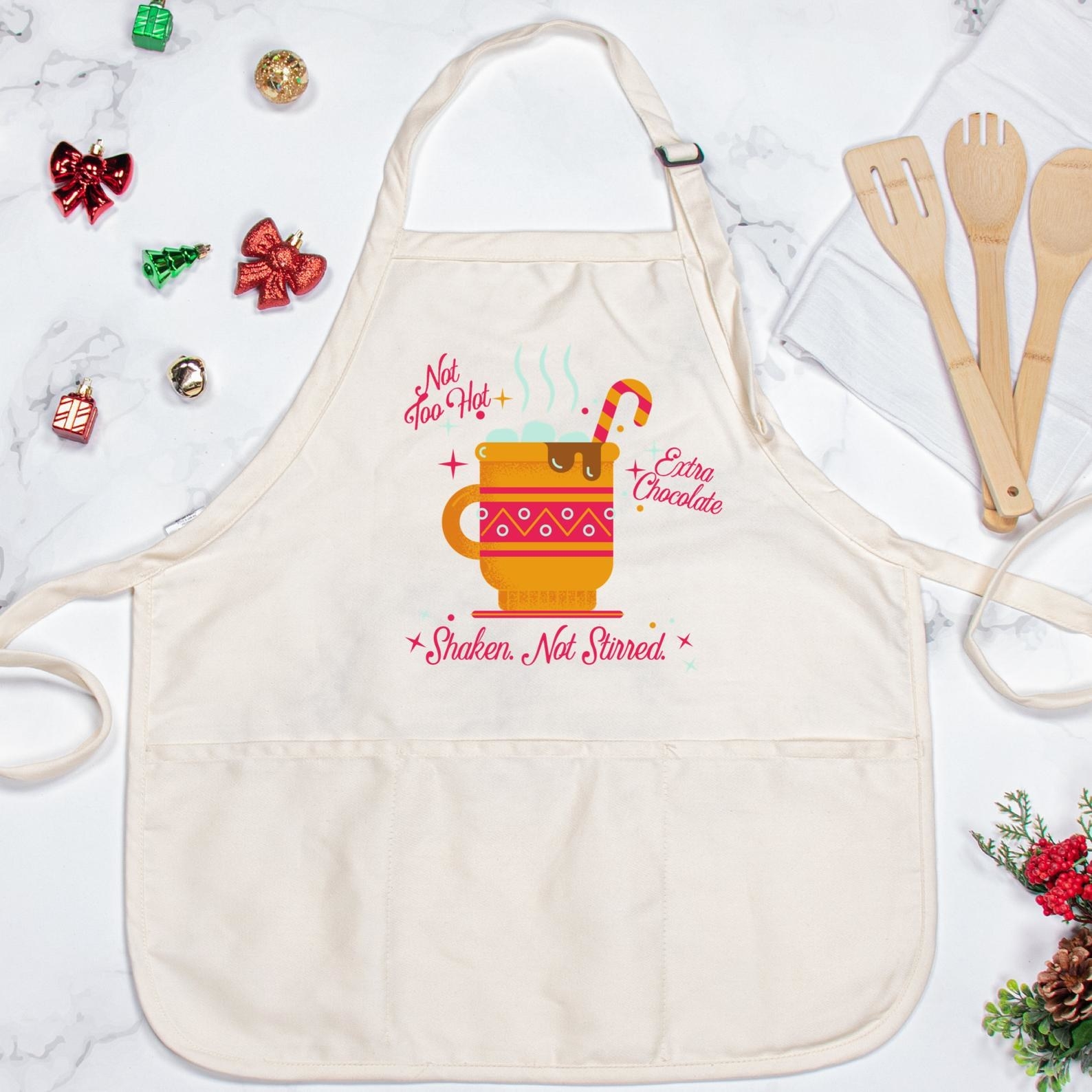 the apron with a mug of hot chocolate on it and the words &quot;not too hot, extra chocolate, shaken not stirred&quot;