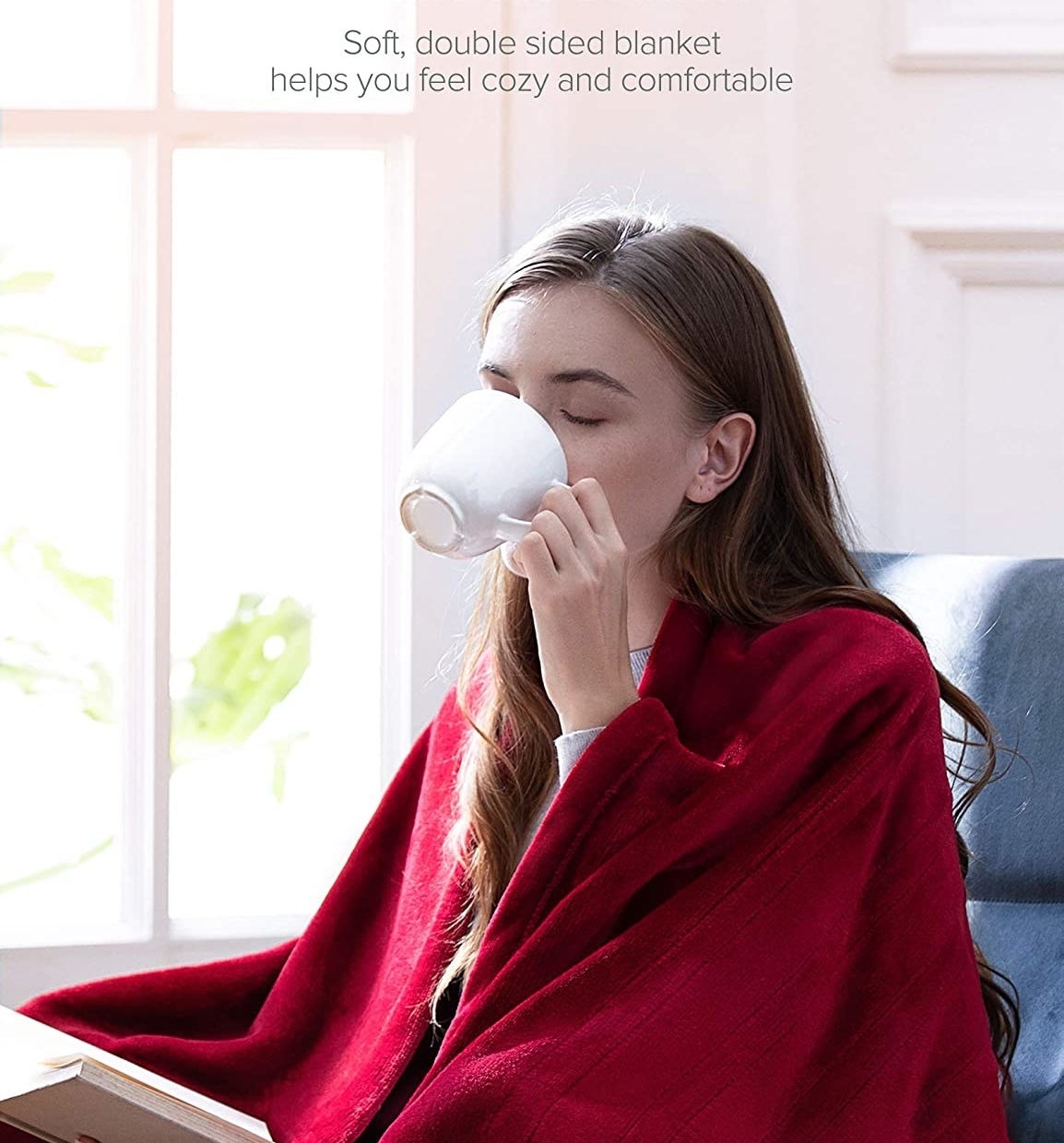 person drinking out of a mug with the blanket wrapped around them