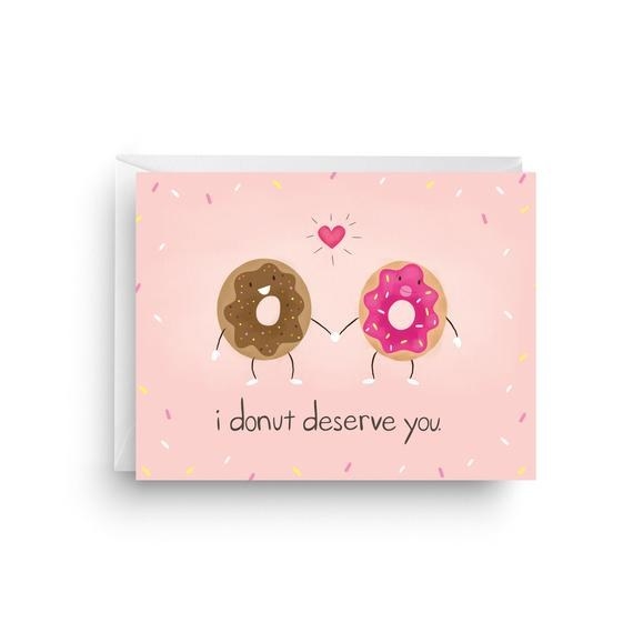 A pink background with sprinkle print, and two anthropomorphic donuts hold hands, with "I donut deserve you" written below