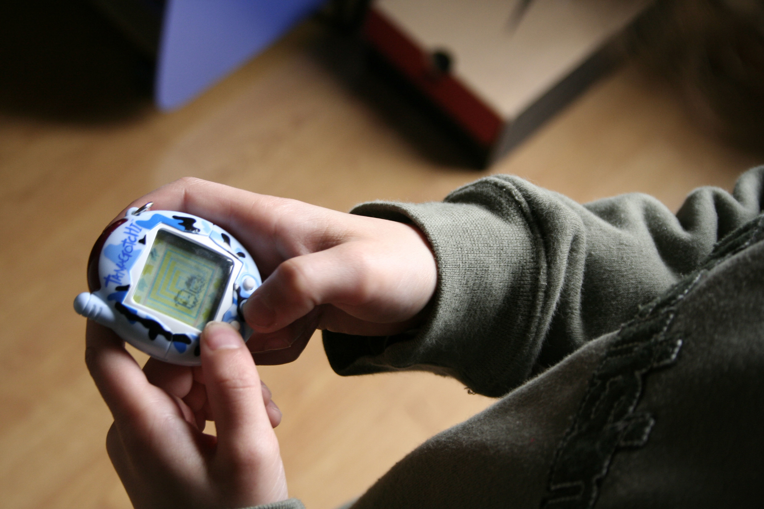 A person holds an older Tamagotchi model in their hands