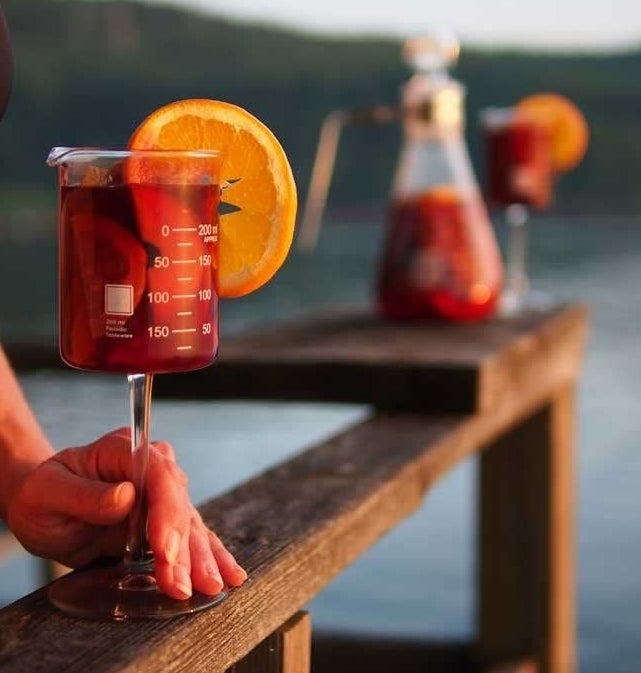 A person holding the beaker cup filled with wine